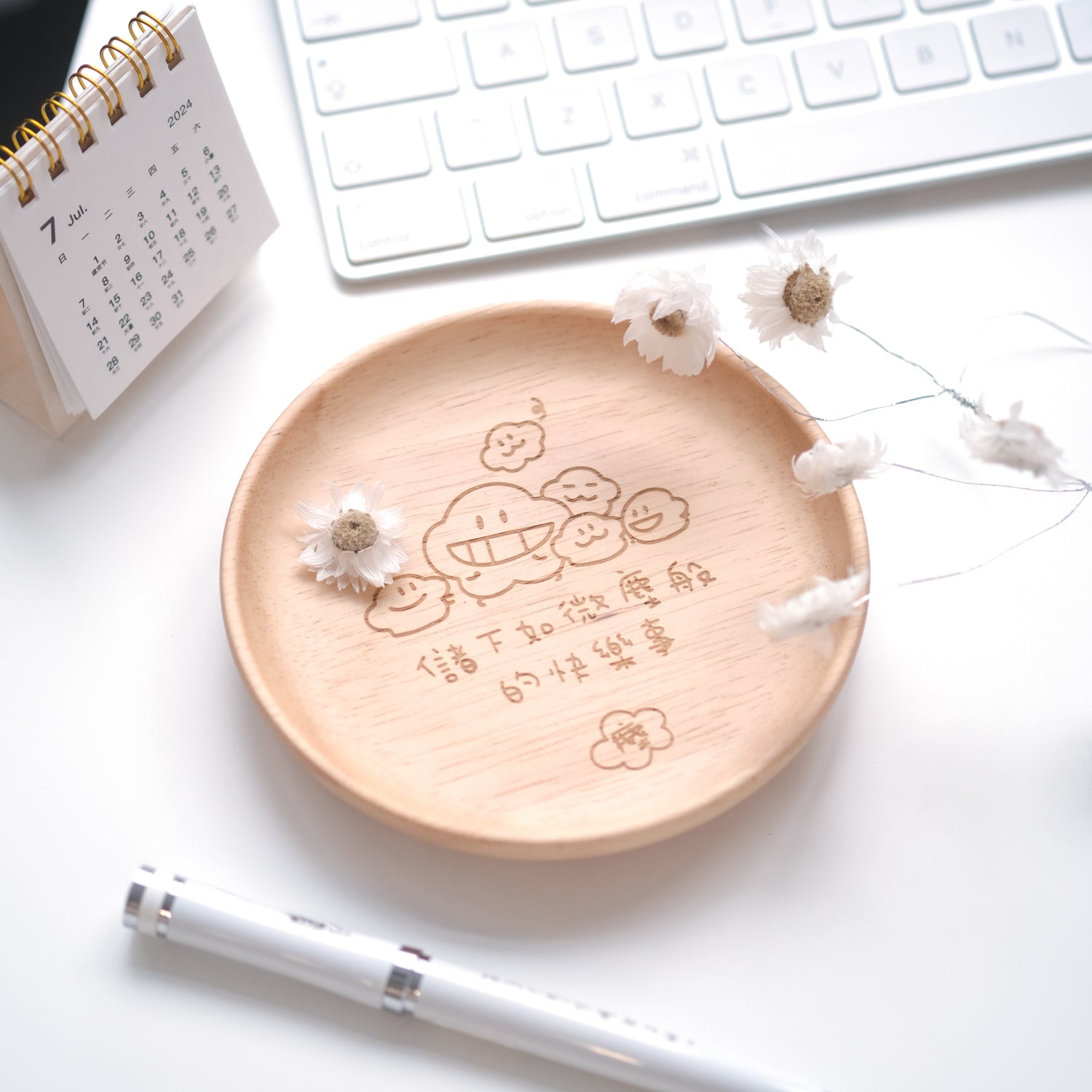 Wooden plate with engraved design on a white desk with keyboard and pen